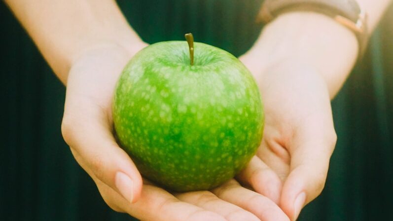 person holding green apple